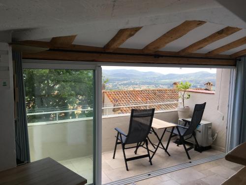 un patio avec une table et des chaises sur un balcon dans l'établissement Studio le Nid, vue mer, village et collines avec terrasse, à Bormes-les-Mimosas