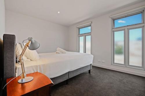 a bedroom with a bed and a lamp on a table at Trendy 3 Level Retreat at North Melbourne with parking in Melbourne