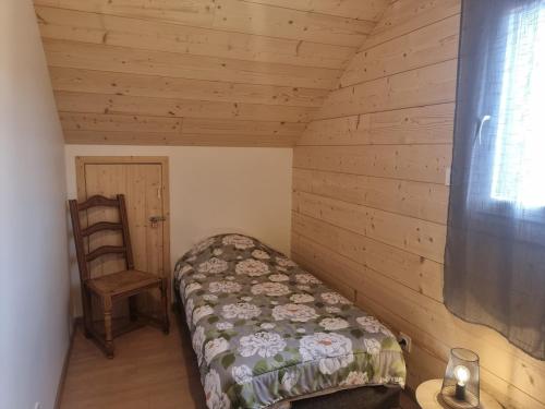 a small bedroom with a bed and a chair at Le nid de Claude et Nadine in Gérardmer