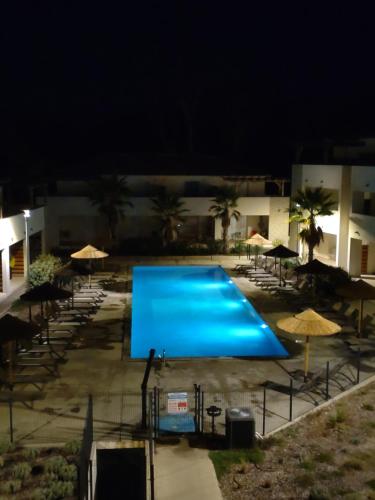 - une grande piscine bleue la nuit avec des parasols dans l'établissement T3 Corse vue mer. pieds dans l'eau N164, à Linguizzetta