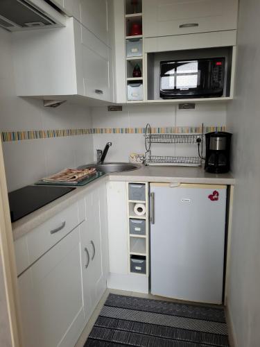 une petite cuisine avec des armoires blanches et un évier dans l'établissement Maison du Centre, à Saint-Jean-de-Monts