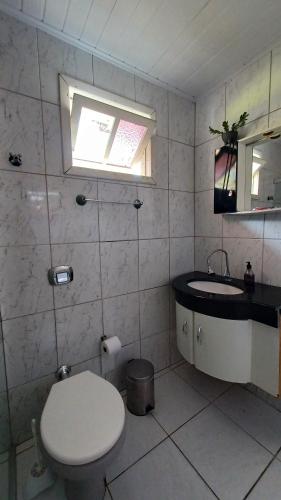 uma casa de banho com um WC, um lavatório e uma janela em Casa das Plantas em Gravatal