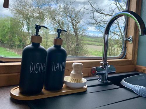 two bottles on a kitchen counter next to a window at The Showman, Luxury Camper in Halford