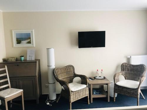 a living room with two chairs and a table and a tv at Hotel Admiral Scheer in Laboe