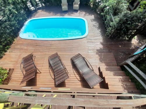 a swimming pool on a wooden deck with three stairs at Pousada Baia Rosa in Praia do Rosa