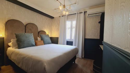 ein Schlafzimmer mit einem großen weißen Bett und einem Kronleuchter in der Unterkunft La Caravelle in Aix-en-Provence