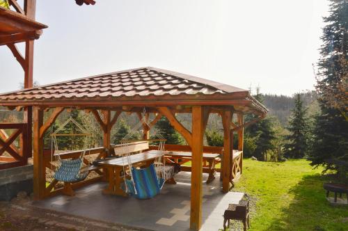 a wooden gazebo with a picnic table and benches at Agroturystyka w Świcie in Tuchola