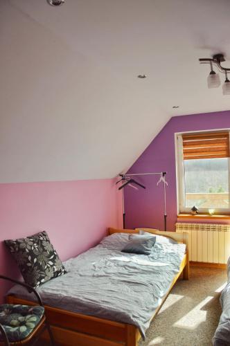 a bedroom with a bed with a purple wall at Agroturystyka w Świcie in Tuchola