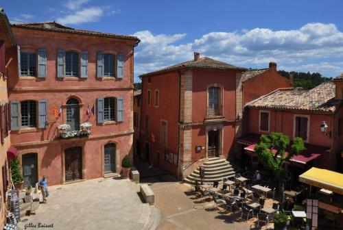 a group of buildings with tables and chairs in a courtyard at Appartement Roussillon in Roussillon