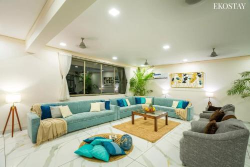 a living room with blue couches and a table at EKOSTAY Luxe - Casa De Atlantis in Alibaug