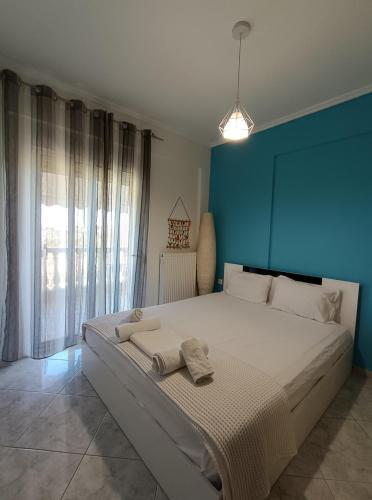 a bedroom with a large bed with a blue wall at Dimar1 Seaside Apartment in Paralia Dionysiou