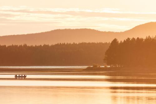 a lake with a couple of benches in the water at Blueberry Lodge 8 personnes in Mjölan