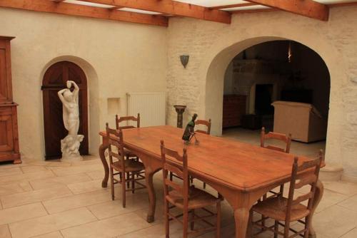 a wooden table and chairs in a room with a statue at La Creullinnerie in Morville
