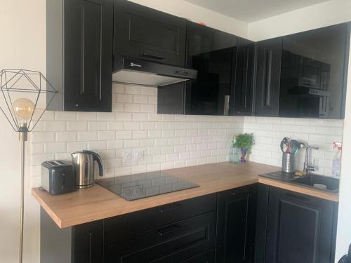 une cuisine avec des armoires noires et un comptoir en bois dans l'établissement Grand Appartement Proche Paris Idéal Paris 2024, à Ivry-sur-Seine