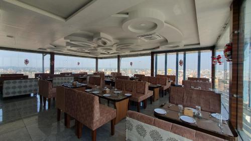 - un restaurant avec des tables et des chaises dans une salle dotée de fenêtres dans l'établissement Anjani Suite, à Janakpur