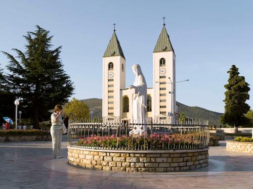 a woman standing in front of a statue in front of a church at Apartman Antony in Čitluk