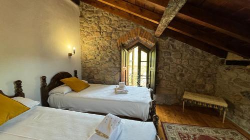 1 dormitorio con 2 camas y pared de piedra en El Molino de Cicera, en Cicera