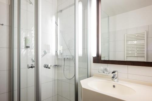 ein Bad mit einer Dusche, einem Waschbecken und einem Spiegel in der Unterkunft Uferdeck - Boutique Hotel in Traben-Trarbach