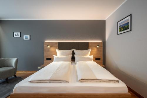 a bedroom with a large bed and a chair at Uferdeck - Boutique Hotel in Traben-Trarbach