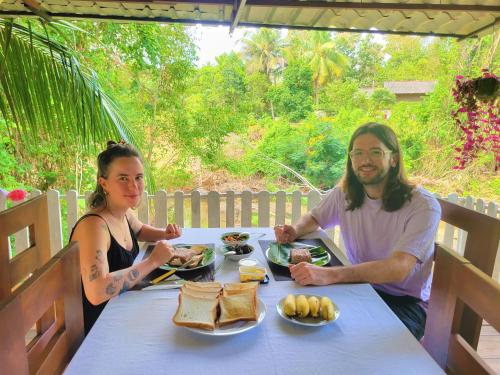 Um homem e uma mulher sentados à mesa com comida. em JAMI River Side Hotel & Yala Safari Place em Tissamaharama