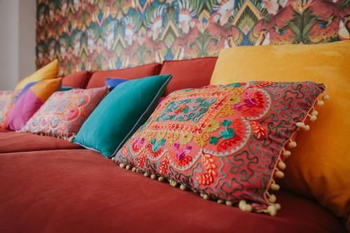 a red couch with colorful pillows on it at Picasso - Spacious Apartment in Old Town Nerja in Nerja