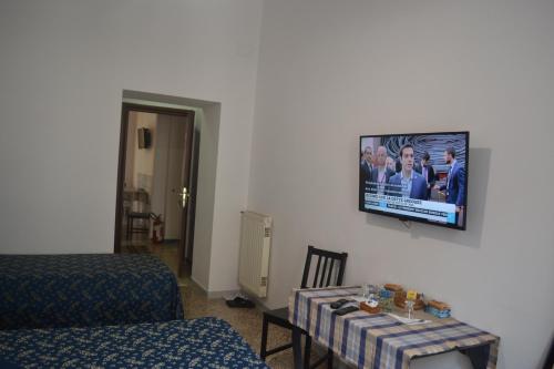 Habitación con mesa y TV en la pared. en Incantoromano guest house, en Roma