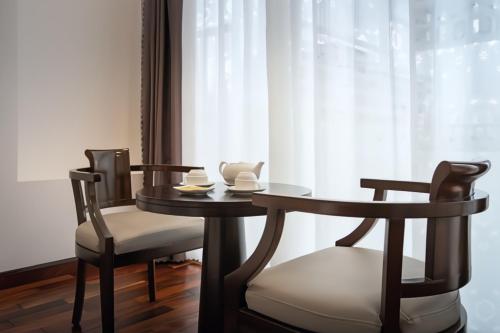 een tafel en twee stoelen met een tafel en een raam bij Hoang Linh Riverside Hotel Danang in Da Nang