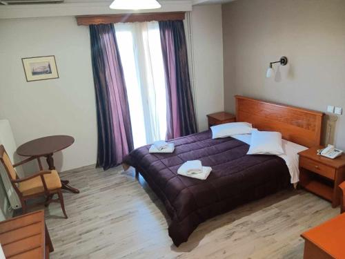 a bedroom with a purple bed and a table and window at Hotel Liberty in Mesolongion