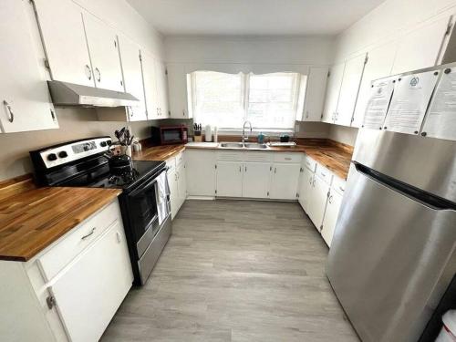 a kitchen with white cabinets and a stainless steel refrigerator at Stay @ The Birchwood/Remodeled & 15 min to DT in Birmingham