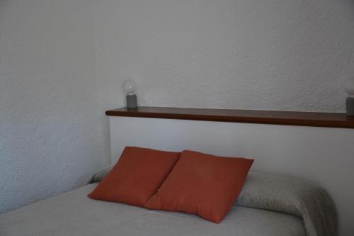 a red pillow sitting on a bed with a shelf at Hotel Misty in Cadaqués