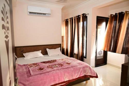 a bedroom with a bed with a pink blanket at Hotel Shree Chandram in Nāthdwāra