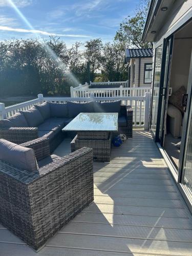 a patio with a couch and a table on a porch at KMH Caravans at Flamingo Land in Kirby Misperton