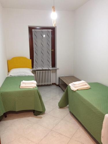 a room with two green beds and a window at Foresto Case Vacanza in Volta Mantovana