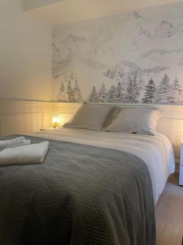 - une chambre avec un grand lit recouvert de montagnes enneigées sur le mur dans l'établissement Magnifique T2 -Au creux du Jura- Saint Claude, à Saint-Claude
