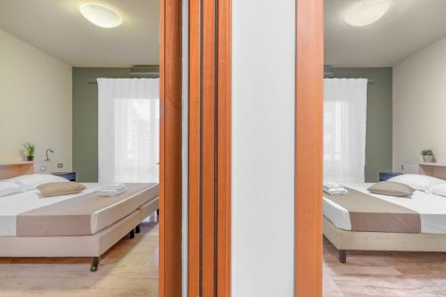 Casa da Suite Fraschini في ميلانو: سريرين في غرفة مع مرآة
