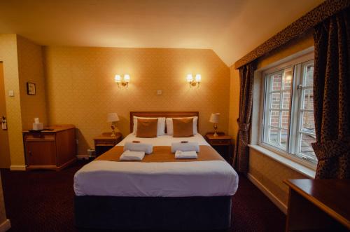 a hotel room with a large bed and a window at Howfield Manor Hotel in Canterbury