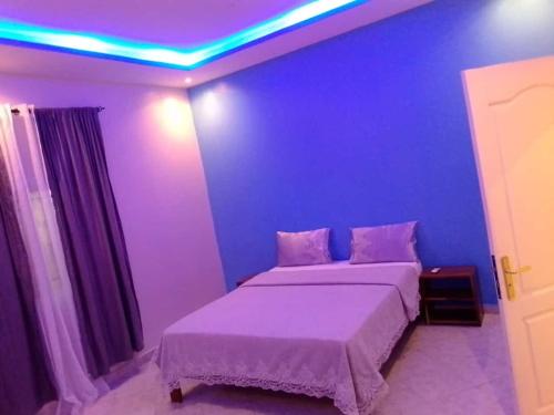 - une chambre dotée d'un lit avec un mur bleu dans l'établissement Villa Fama, à Mbour