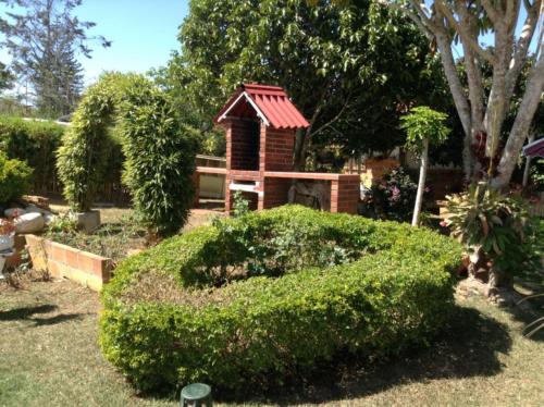 a small house with a red roof in a garden at Villa Liliana Lodge Mesa de los Santos in Los Santos