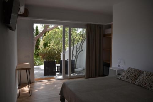 a bedroom with a bed and a sliding glass door at Hotel Misty in Cadaqués