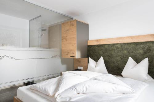 a bedroom with a bed with white sheets and pillows at Landhaus Bergland in Obsteig