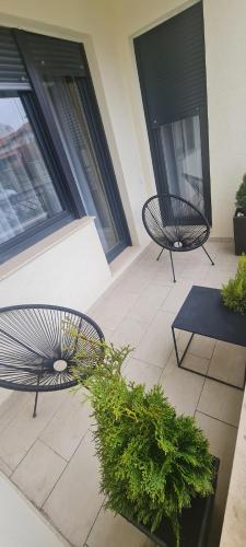 a patio with two chairs and a table and plants at Harmony Apartmani Arandjelovac in Arandjelovac