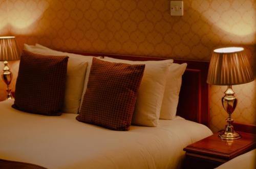 a bedroom with a bed with pillows and two lamps at Howfield Manor Hotel in Canterbury