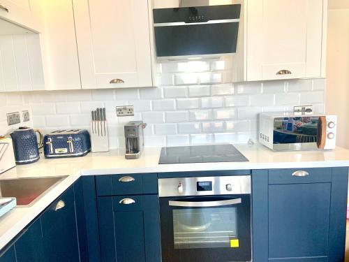 a kitchen with blue cabinets and a stove top oven at Winners of 2025 traveller Award, Elegant two bedroom city central apartment with Netflix & WiFi in Leeds