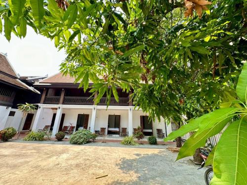 a building with a lot of trees in front of it at Residence Boutique Hotel in Luang Prabang