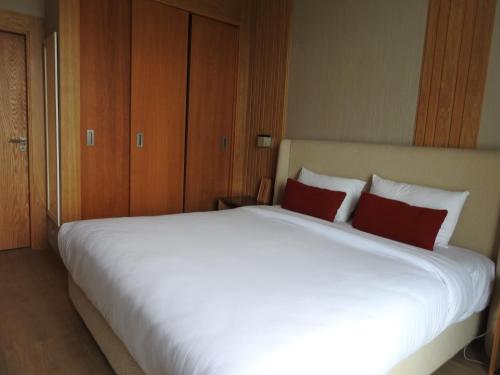 a large white bed with two red pillows on it at Anfa Place, Luxury Apartment just renovated, Ocean View in Casablanca