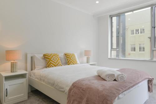 a white bedroom with a bed and a window at Great Location! Darling Harbour Superb 2BR Apt in Sydney