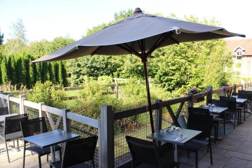 a patio with tables and chairs under an umbrella at Clos De La Vaupalière - Rouen in La Vaupalière
