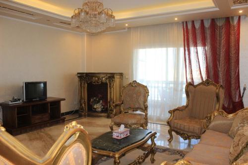 ein Wohnzimmer mit einem Sofa, Stühlen und einem TV in der Unterkunft ALMADIAFAH APARTMENT - المضيفة للوحدات الفندقيه in Mansoura