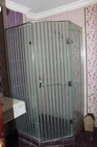 a glass shower door in a room with a wall at ALMADIAFAH- No forigner المضيفة للوحدات الفندقيه -عرب فقط in Mansoura