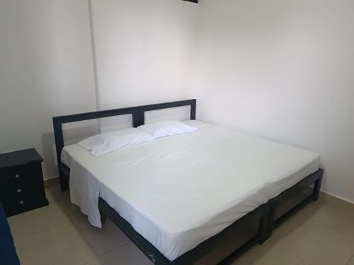a bed with white sheets and pillows on it at Hospedaje Casa Cultural Saberes in Neiva